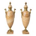 Pair of ornate urns with marble bodies and gold accents on a white background